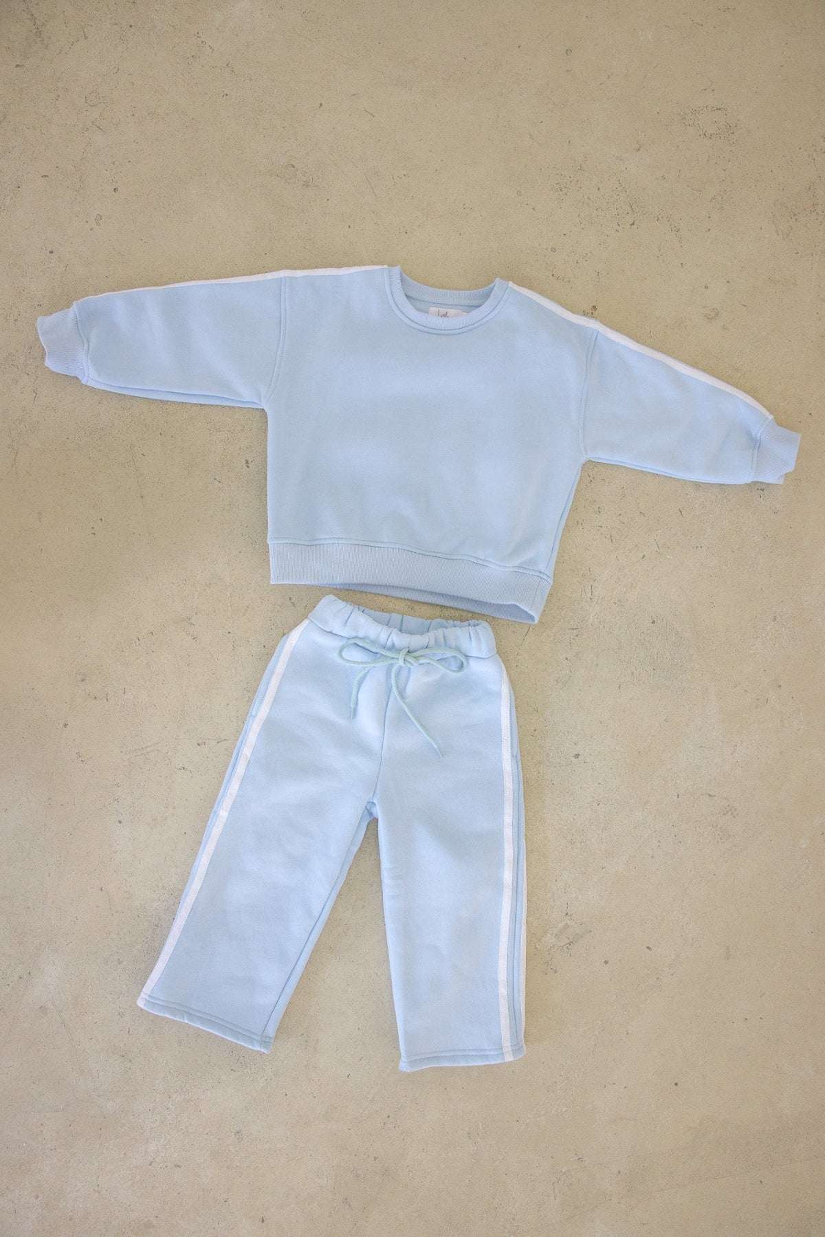 Light blue sweatshirt and pants set on a beige background