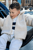 Child wearing a beige fleece jacket sitting on playground equipment | Ryan is 100cm tall and wears size 3Y.