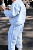 Person wearing a light blue tracksuit standing on a street. | Alex is 2'6