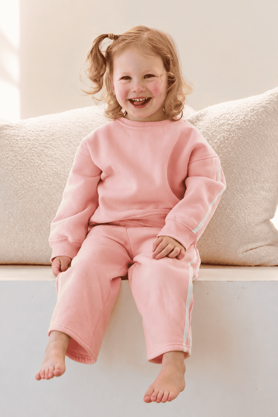 Child wearing pink pajamas sitting on a couch