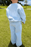 Person wearing a light blue tracksuit with 'Little' text on the back, standing on grass. | Alex is 2'6