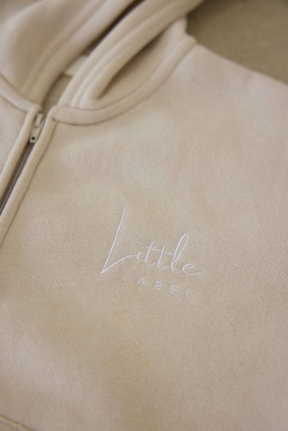 Beige hoodie with 'Little Label' embroidery on a beige background