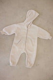 Beige baby onesie with a hood on a beige surface