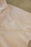 Close-up of beige fabric with 'Little Label' embroidered on it.