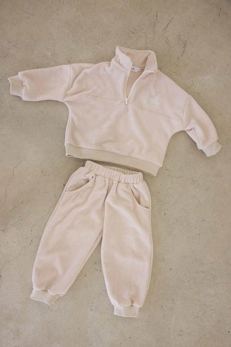 Beige fleece tracksuit on a beige textured surface