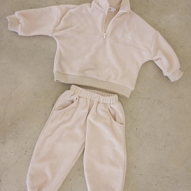 Beige fleece tracksuit on a beige textured surface