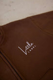 Brown garment with 'Little Label' embroidery on a light background