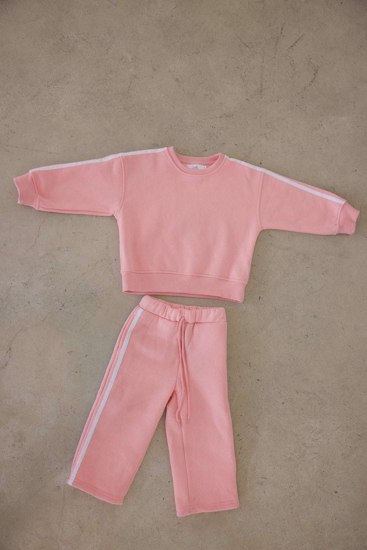 Pink sweatshirt and pants set on a beige floor