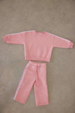 Pink sweatshirt and pants set on a beige floor