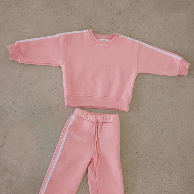 Pink sweatshirt and pants set on a beige floor
