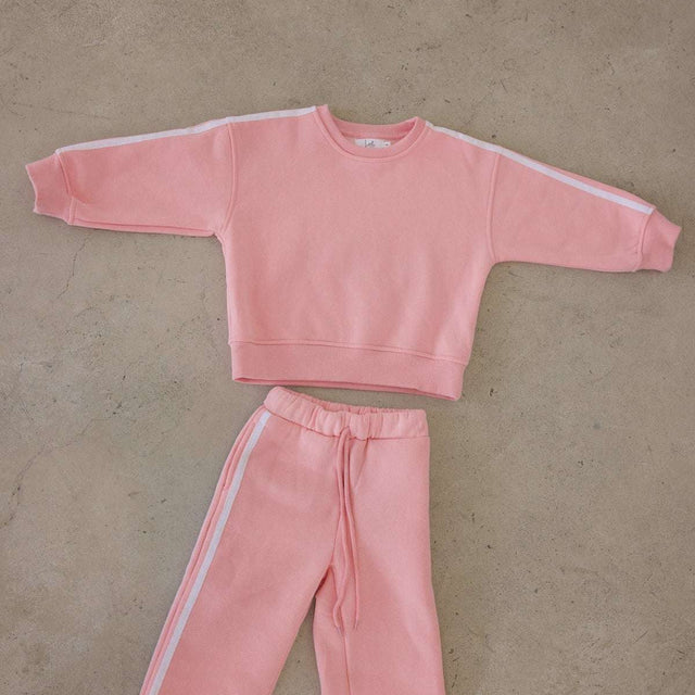 Pink sweatshirt and pants set on a beige floor