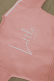 Pink sleeveless top with 'Little Label' text on a beige background