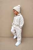 Child wearing a beige fleece outfit with a matching beanie against a beige background | Ryan is 3'3
