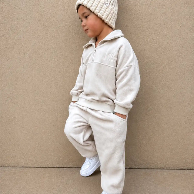 Child wearing a beige fleece outfit with a matching beanie against a beige background | Ryan is 3'3" (100cm), wears size 3Y