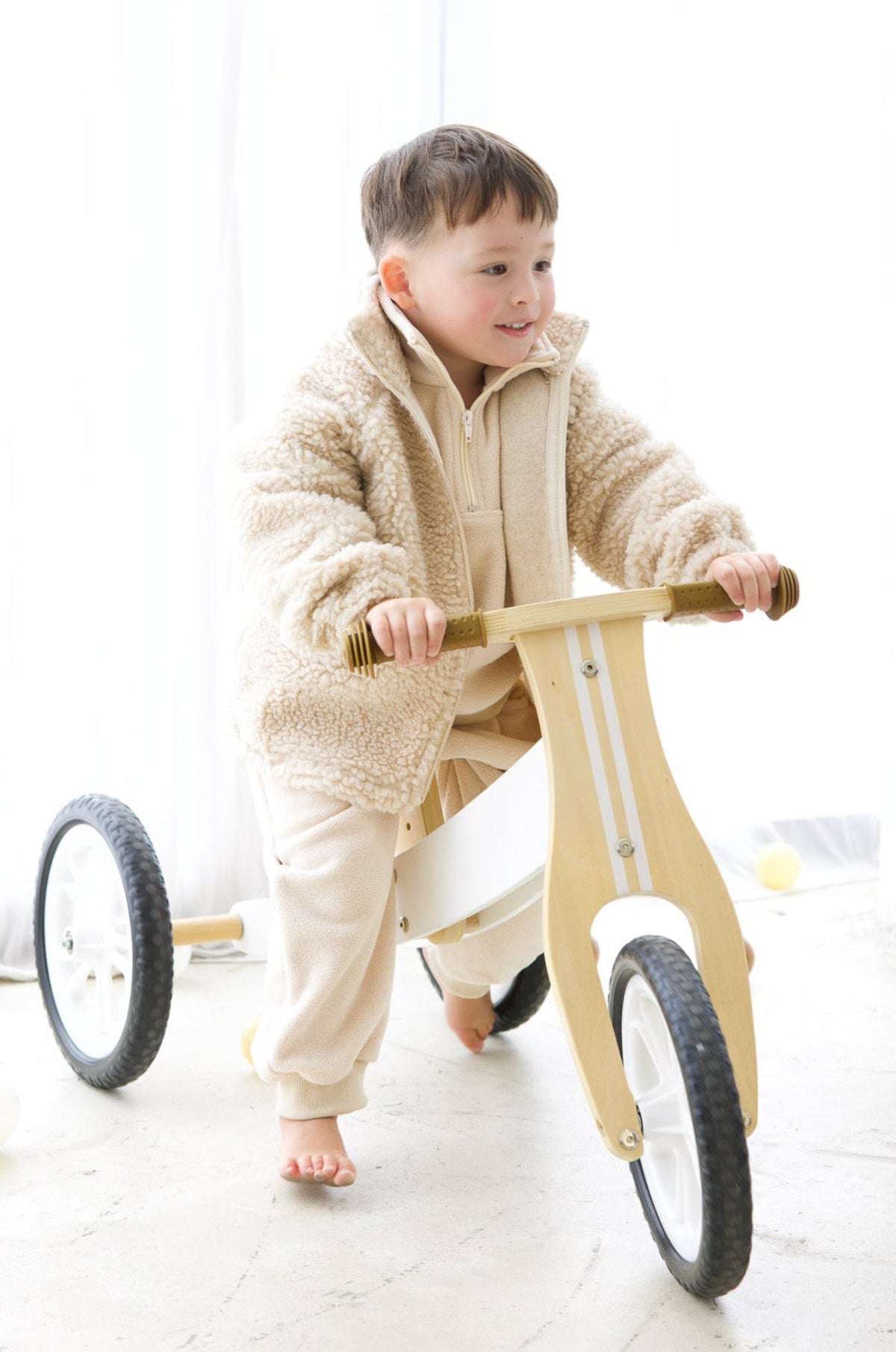 Child riding a wooden balance bike indoors | Ryan is 3'3