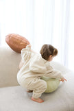Child in a white onesie playing with a football on a light-colored couch | Sophie is 2'7