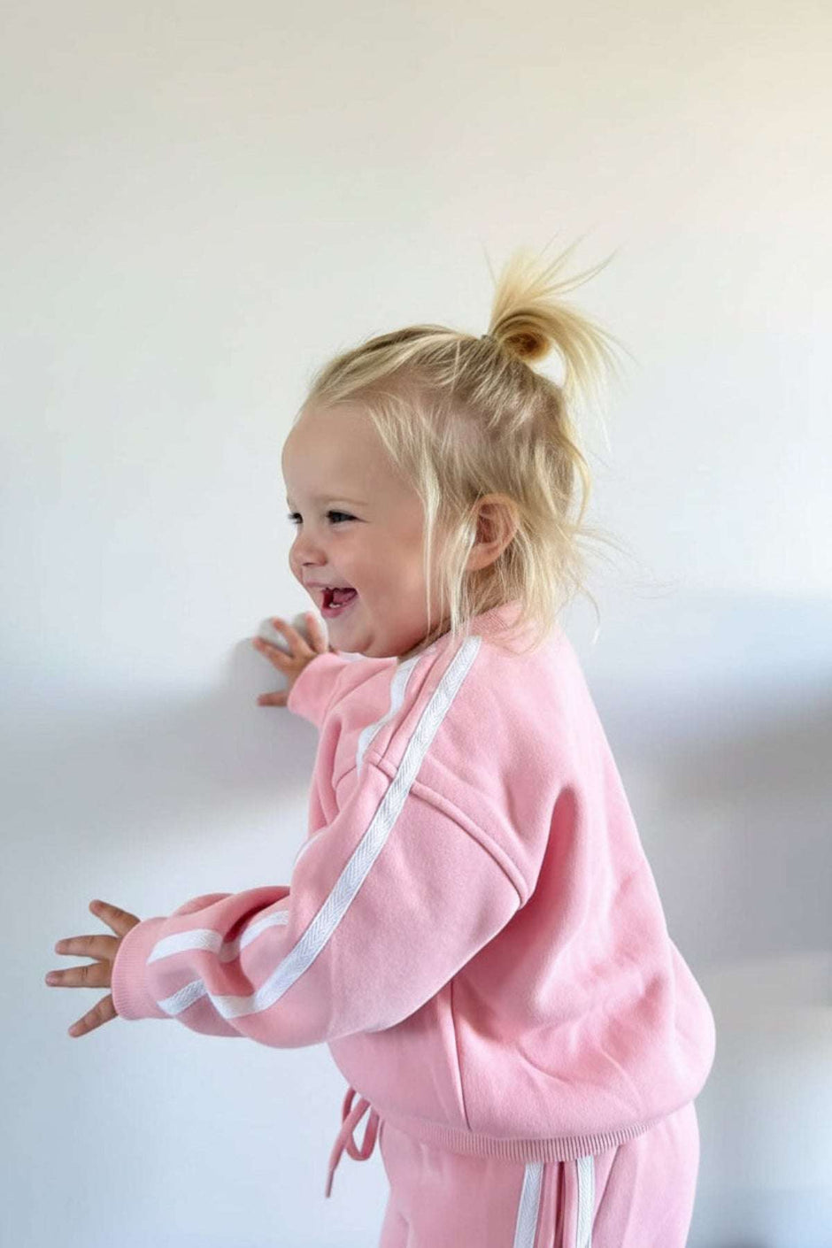 Child in a pink outfit with white stripes on a plain background