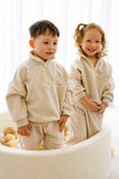 Two children wearing matching beige fleece outfits standing in a bright room. | Elyce is 3'2 (97cm), wears size 3Y